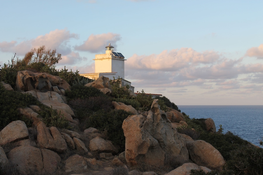 Un faro su una costa rocciosa con il mare sullo sfondo.