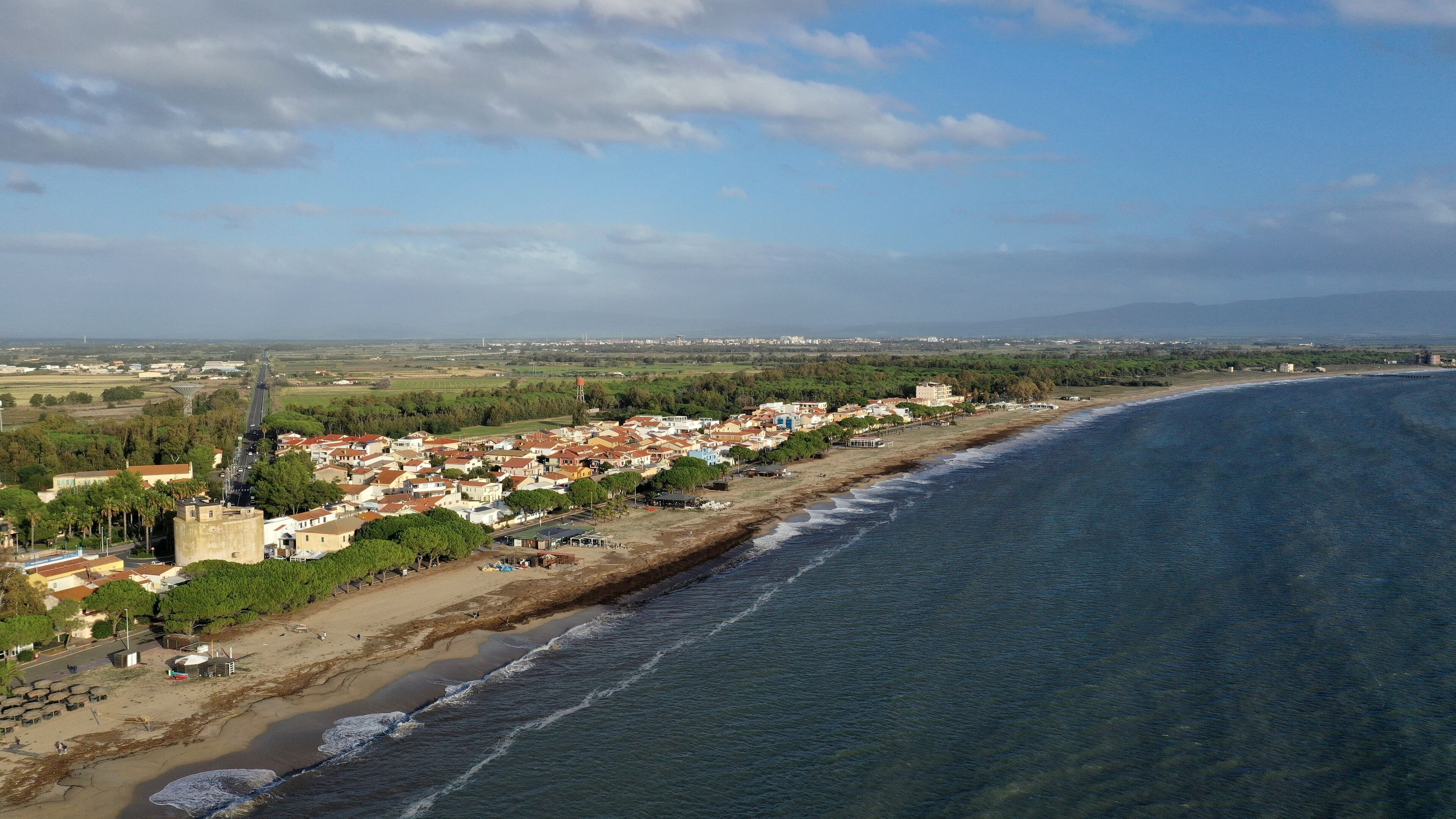 A coastal town with a beach, houses, and a distant mountain range.