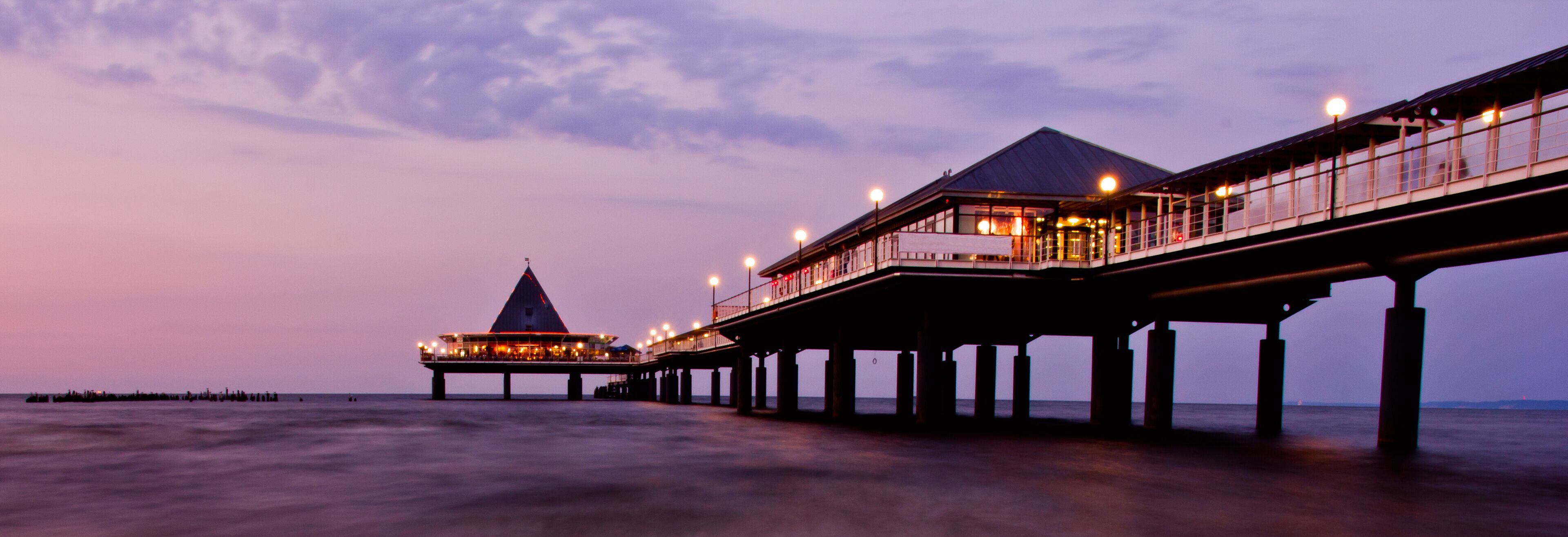 A pier extending into the water with a restaurant and a tower structure at the end.