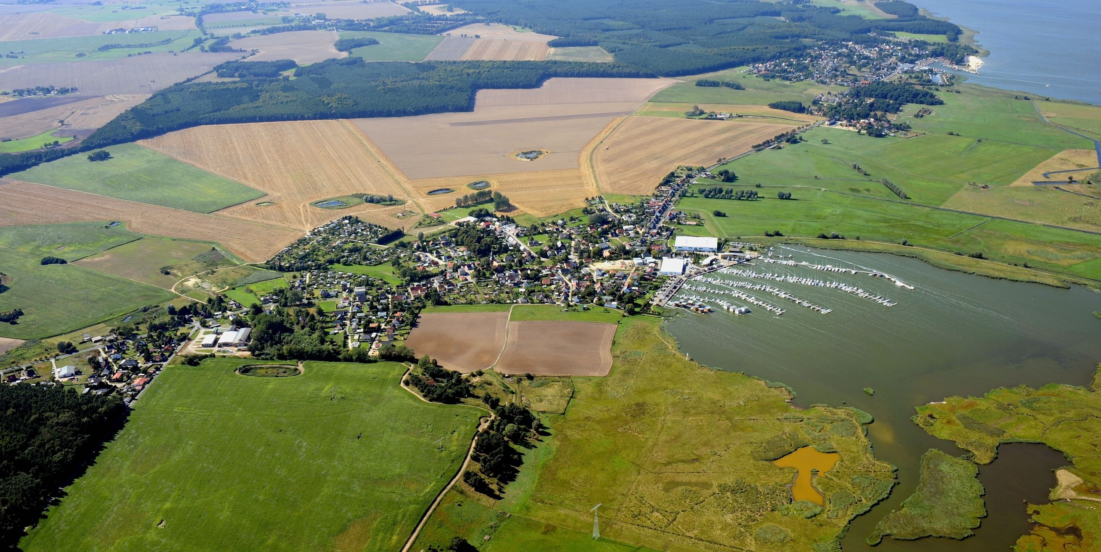 An aerial view of a coastal town with farmland, a harbor, and a river.