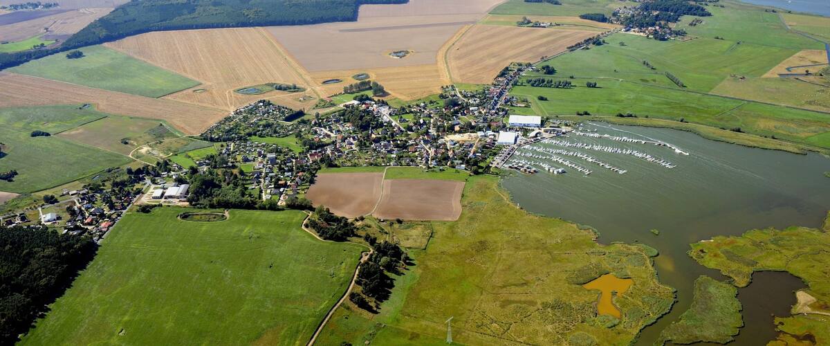 An aerial view of a coastal town with farmland, a harbor, and a river.