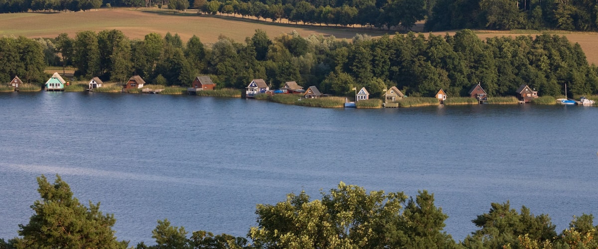 A lake with houses along the shore and a sailboat in the water.