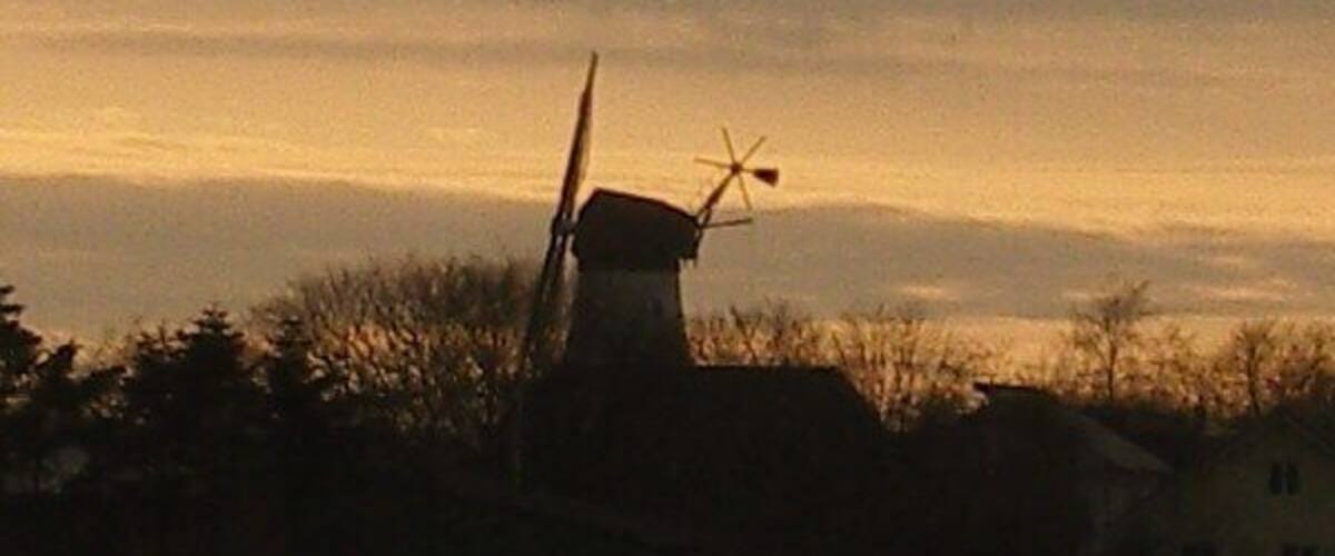 A windmill silhouetted against a sunset sky.