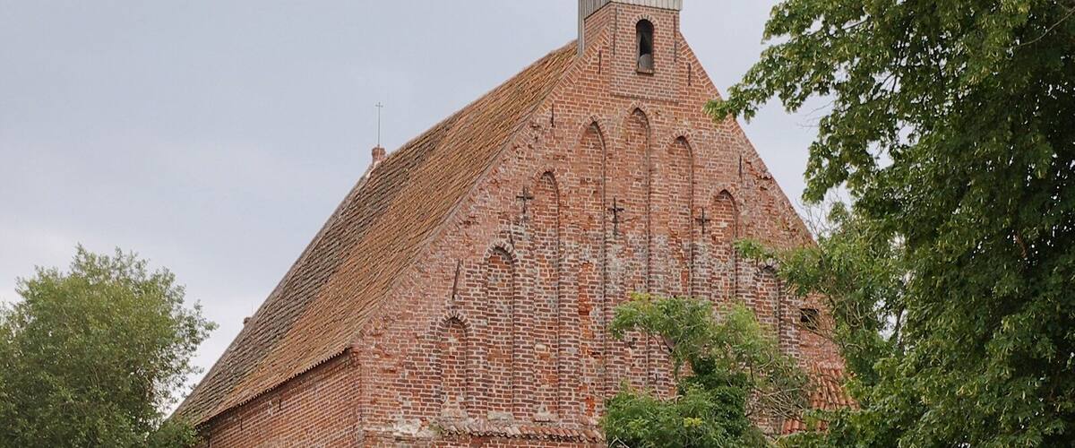 A historic brick church with a bell tower and a red barn.