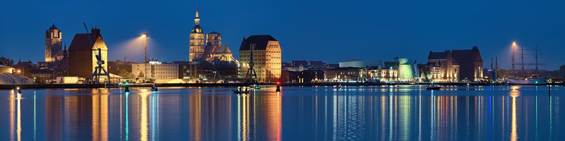 Stralsund, Germany. Panoramic view of the North Harbor in dusk with St. James Church (left), St. Nicholas Church (center), historical warehouses (right).