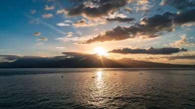 A sunset over a calm sea with mountains in the background.