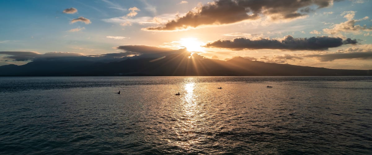 A sunset over a calm sea with mountains in the background.