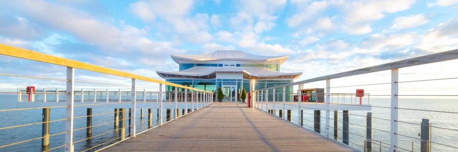 Eine Uferpromenade, die zu einem modernen Gebäude mit markanter Architektur führt.
