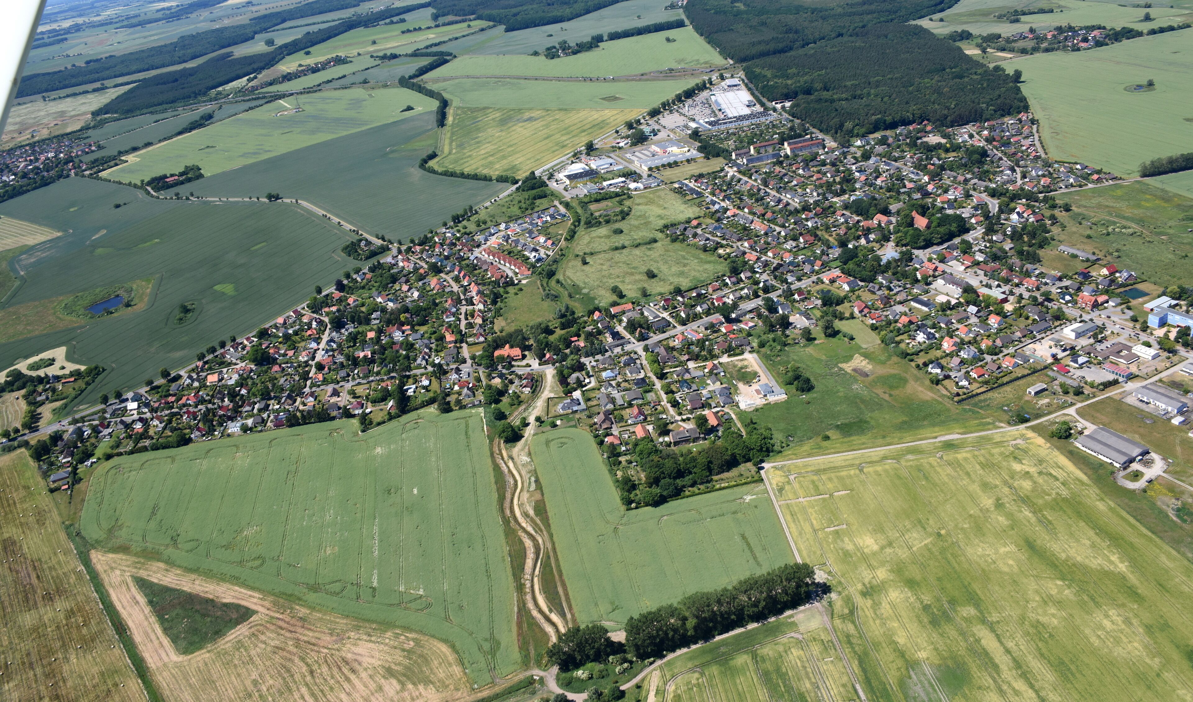 An aerial view of a rural town with fields, roads, and scattered buildings.