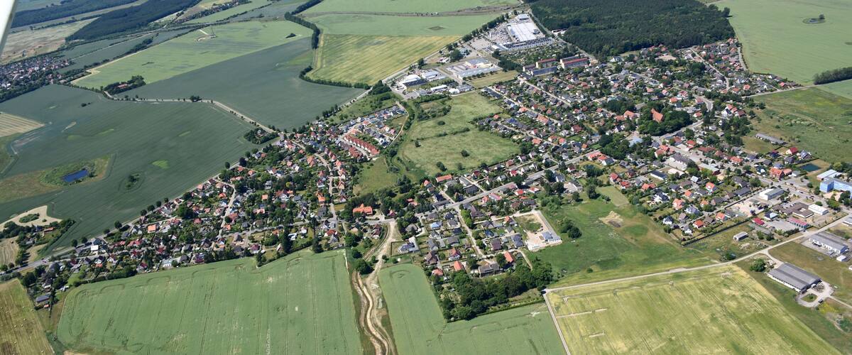 An aerial view of a rural town with fields, roads, and scattered buildings.