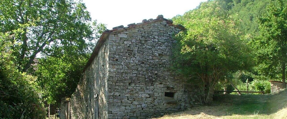 A stone building surrounded by trees and grass.