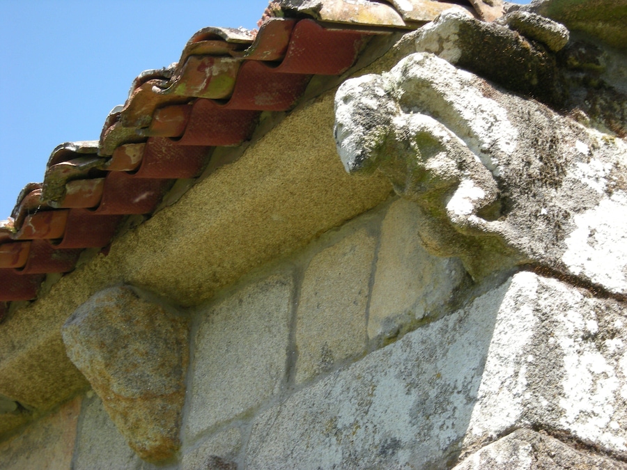 Un mur de pedra erosionat amb teules.