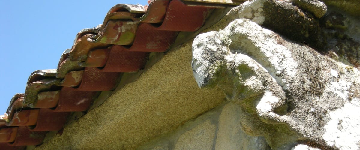 A weathered stone wall with a tiled roof.