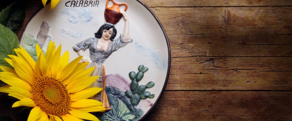 A ceramic plate with a woman holding a jug, surrounded by sunflowers and cacti.
