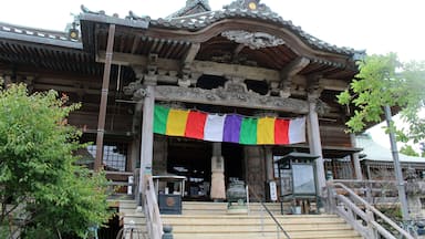 A traditional Japanese building with ornate wooden architecture and a colorful flag.