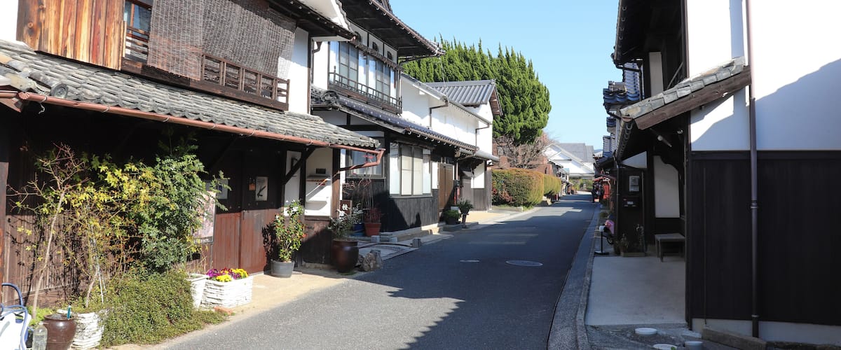 A narrow street lined with traditional wooden houses with tiled roofs.