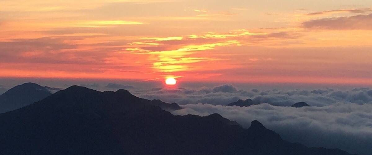 A mountain range with a sunset over the clouds.