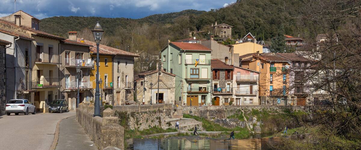 A riverside town with historic buildings, a stone wall, and a clear sky.