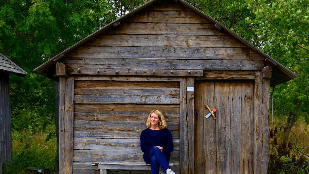 Visby, Gotland, Sweden A woman sits by a fishing hut by the sea.