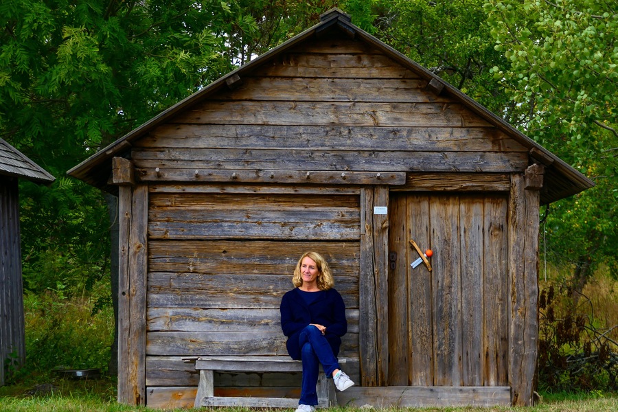 Visby, Gotland, Sweden A woman sits by a fishing hut by the sea.