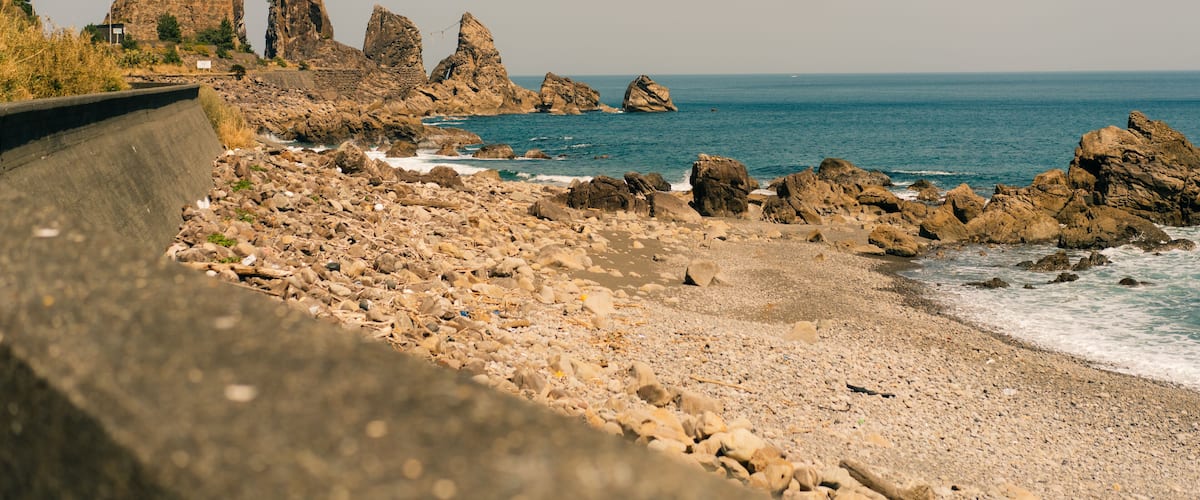 A rocky coastline with prominent rock formations and a calm sea.