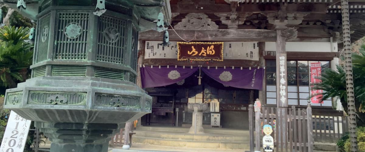 A traditional Japanese building with a stone lantern and a sign with Japanese characters.
