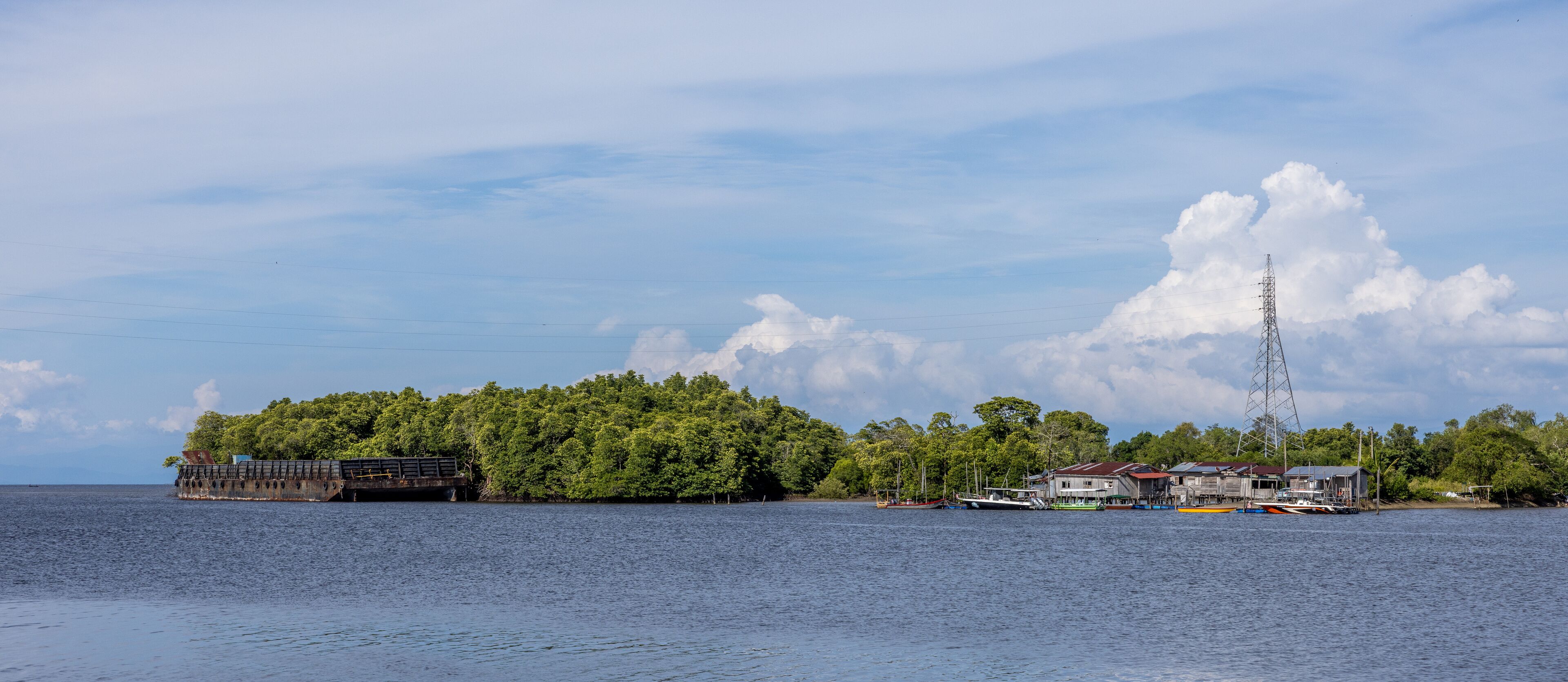 A coastal scene with a dock, a large ship, and a power transmission tower.