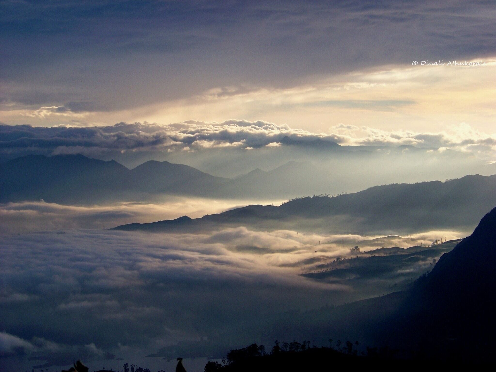 A mountainous landscape with layers of clouds and mist.