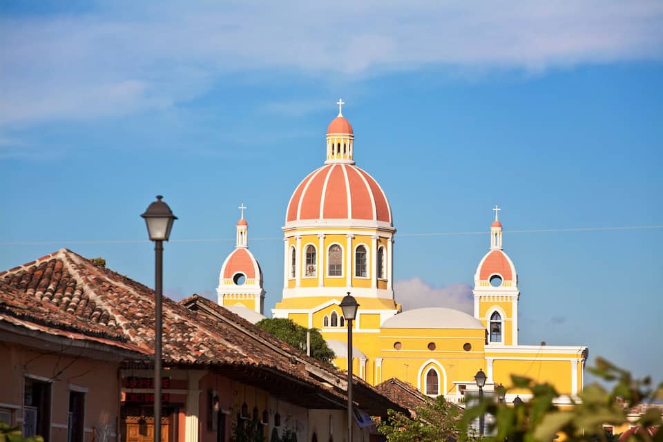 A yellow church with a red dome and a bell tower.