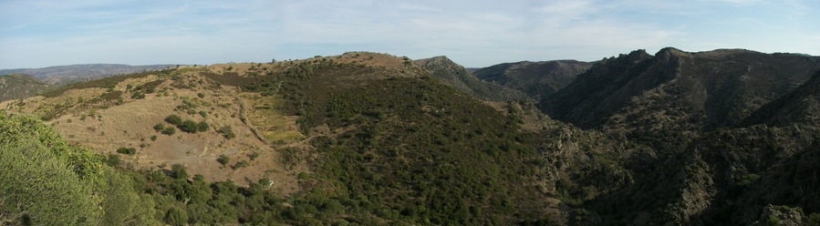 Paisagem montanhosa com terreno acidentado e vegetação escassa.