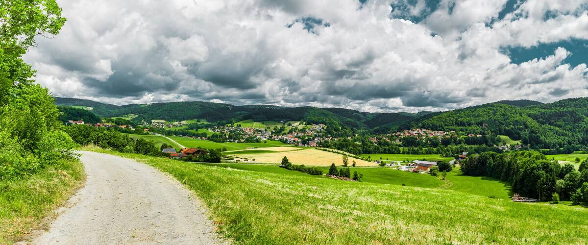 A rural landscape with a winding road, green fields, and a village nestled among hills.