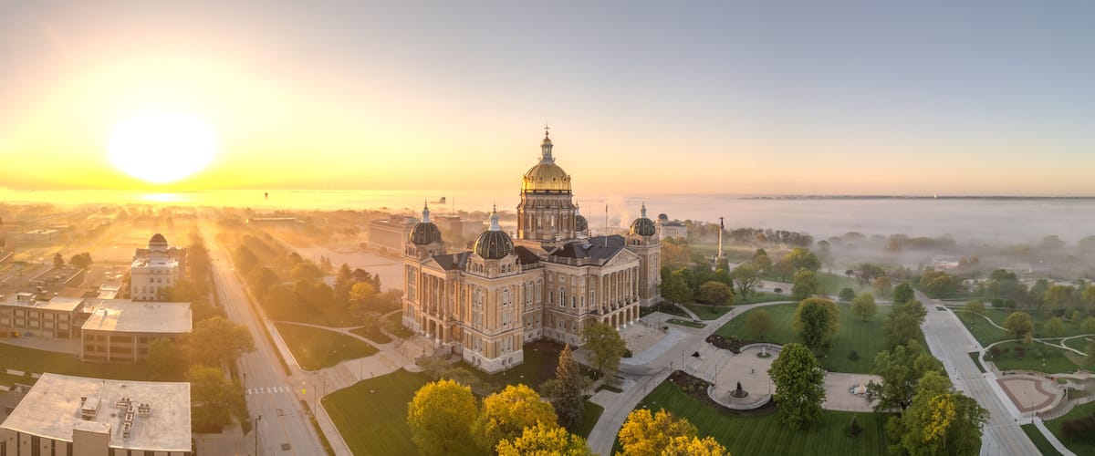 A grand building with domes, surrounded by a park and a river.
