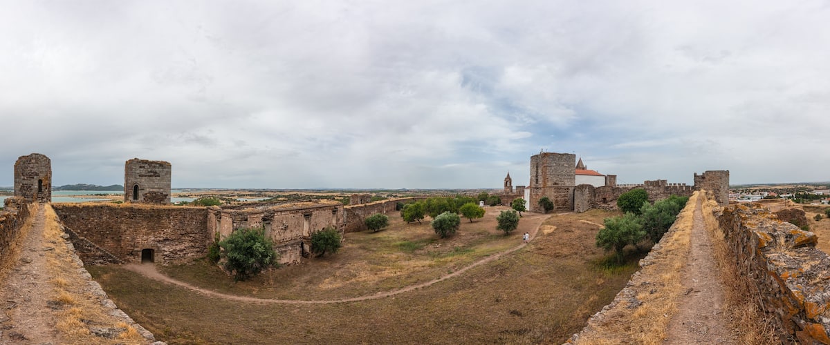 Ancient stone walls, a tower, and a distant view of a city.