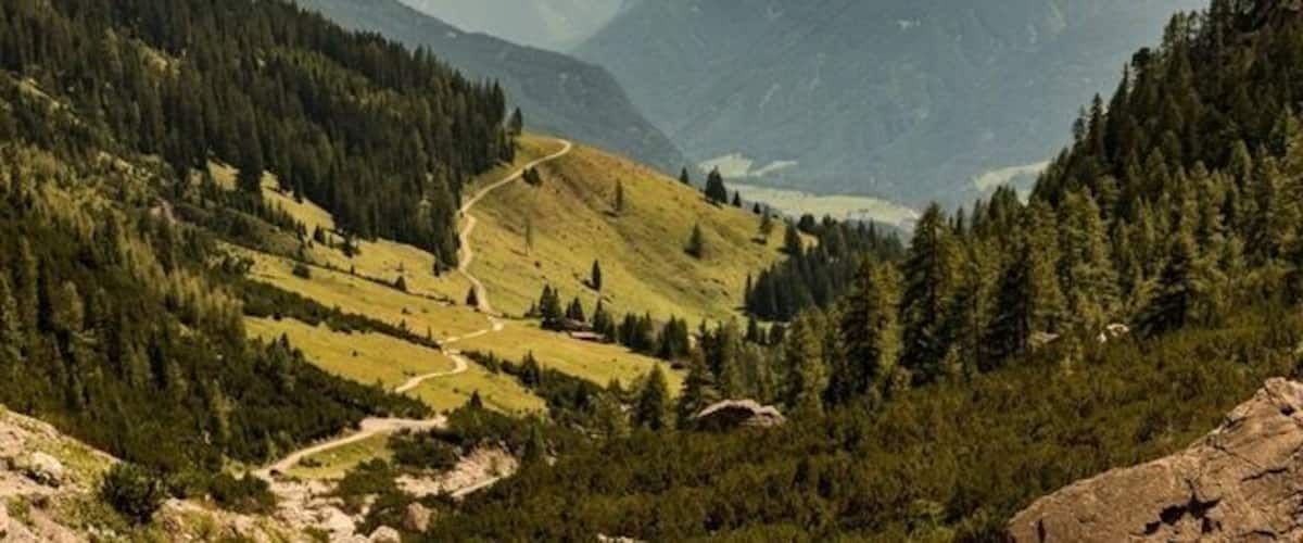 Ein Bergertal mit einer kurvenreichen Straße, dichten Wäldern und einem See.