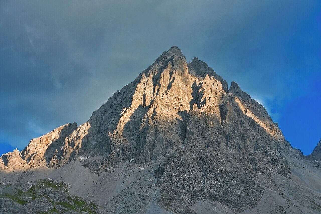 July 2015 

Dremelspitze, Lechtaler Alps 

Dremelspitze with 2.733 m summit is one of the peaks in Lechtaler Alps which can be ascended without climbing or special gear (of course it is not an easy walk either). It is located between the Hanauer Huette and Steinsee-Huette with saddle of some 2.500 meters both on west and east side of this beauty. 
It is made of limestone Dolomite as the whole Lechtaler Alps so it is white greyish during the day, but in the golden hour it gets a cosy warm Colour thanks to the descending sun. 