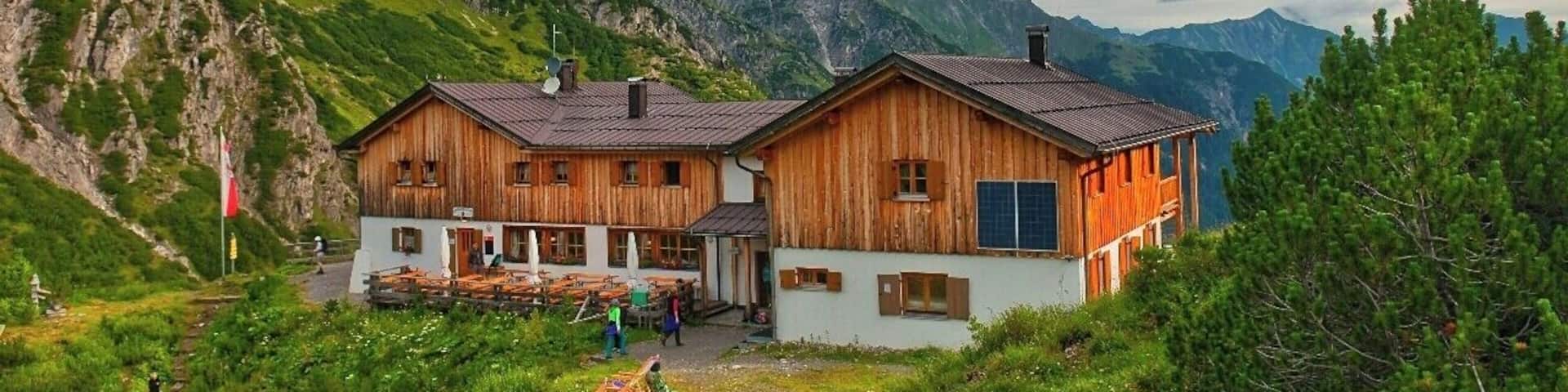A wooden chalet with a mountain backdrop.