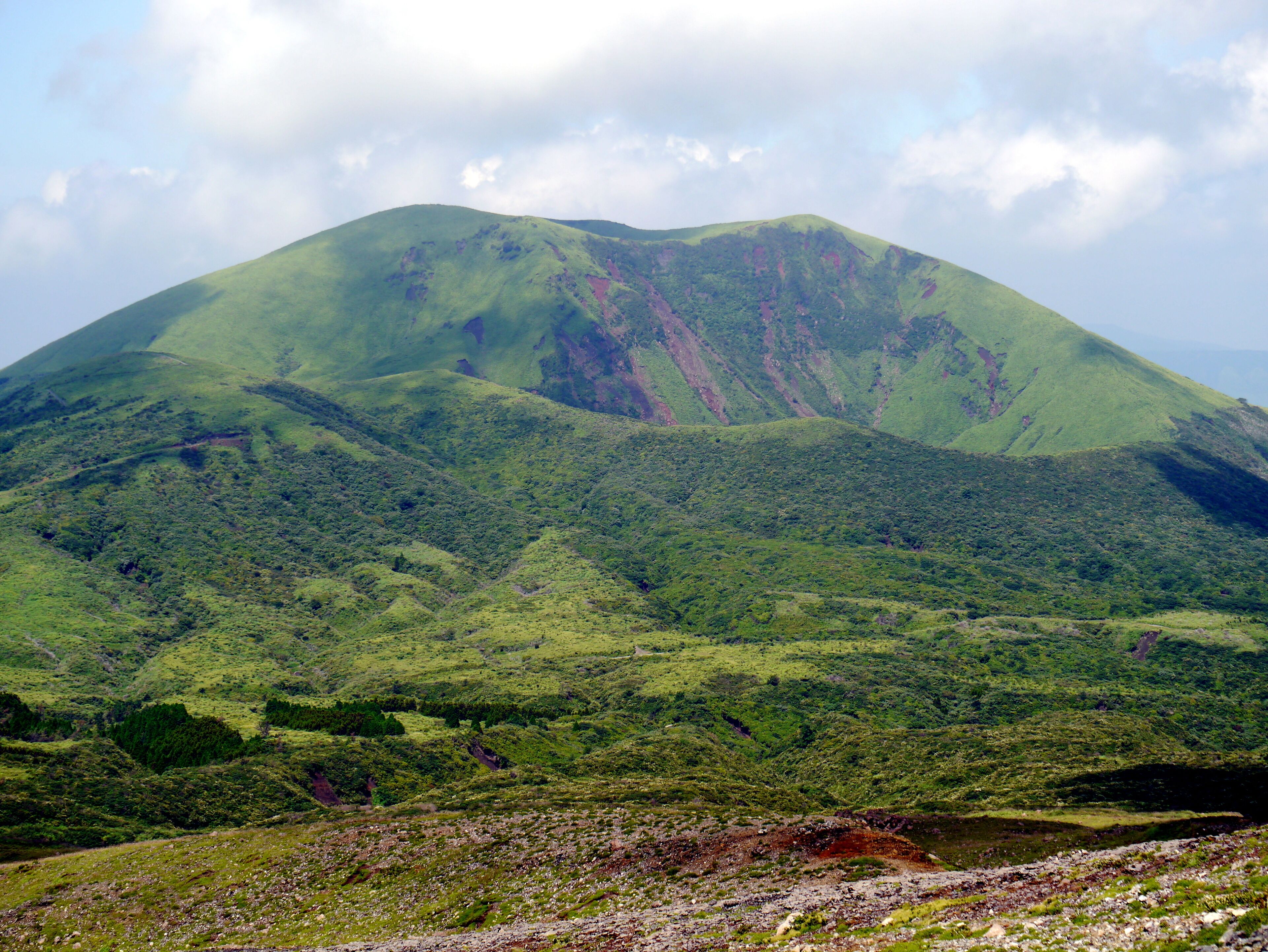 A green mountain with a river at its base.