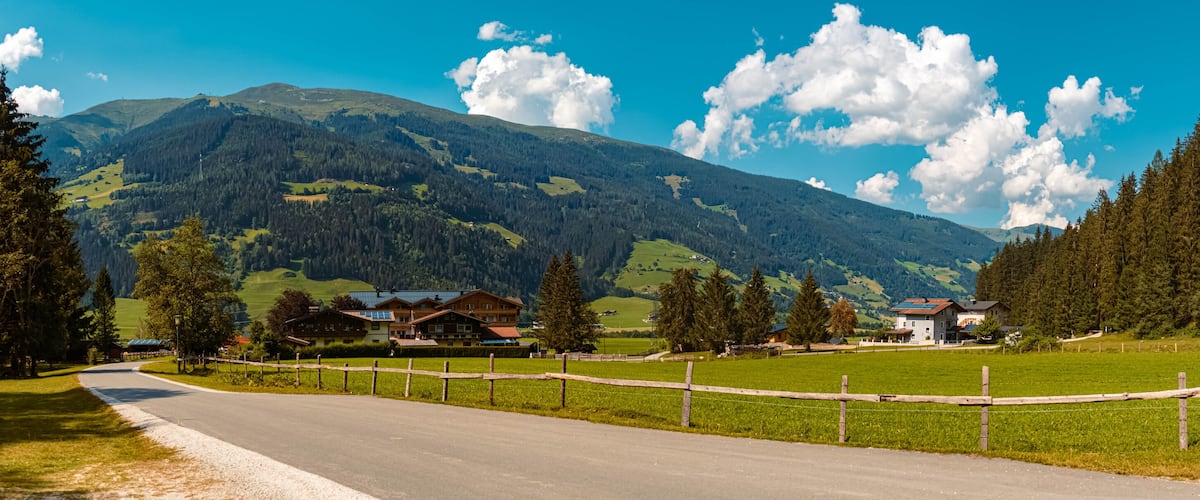 A rural road with houses and a mountain backdrop.
