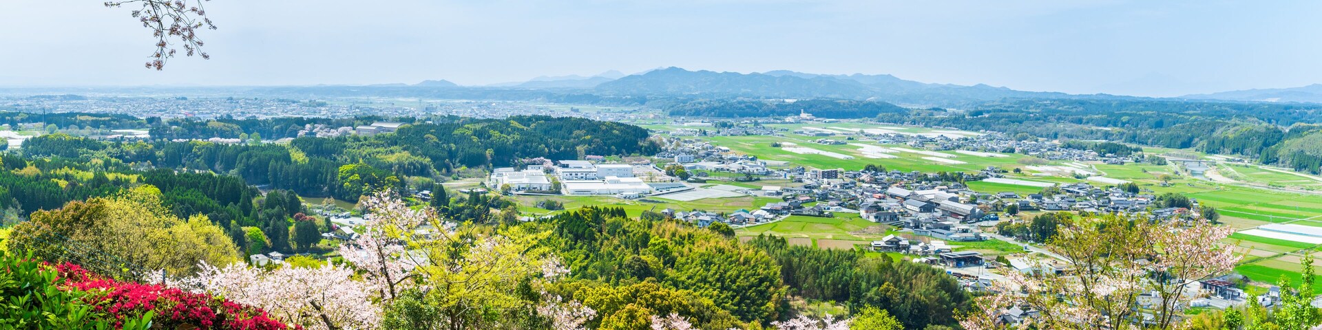 Uma cidade rodeada por campos verdes e montanhas.