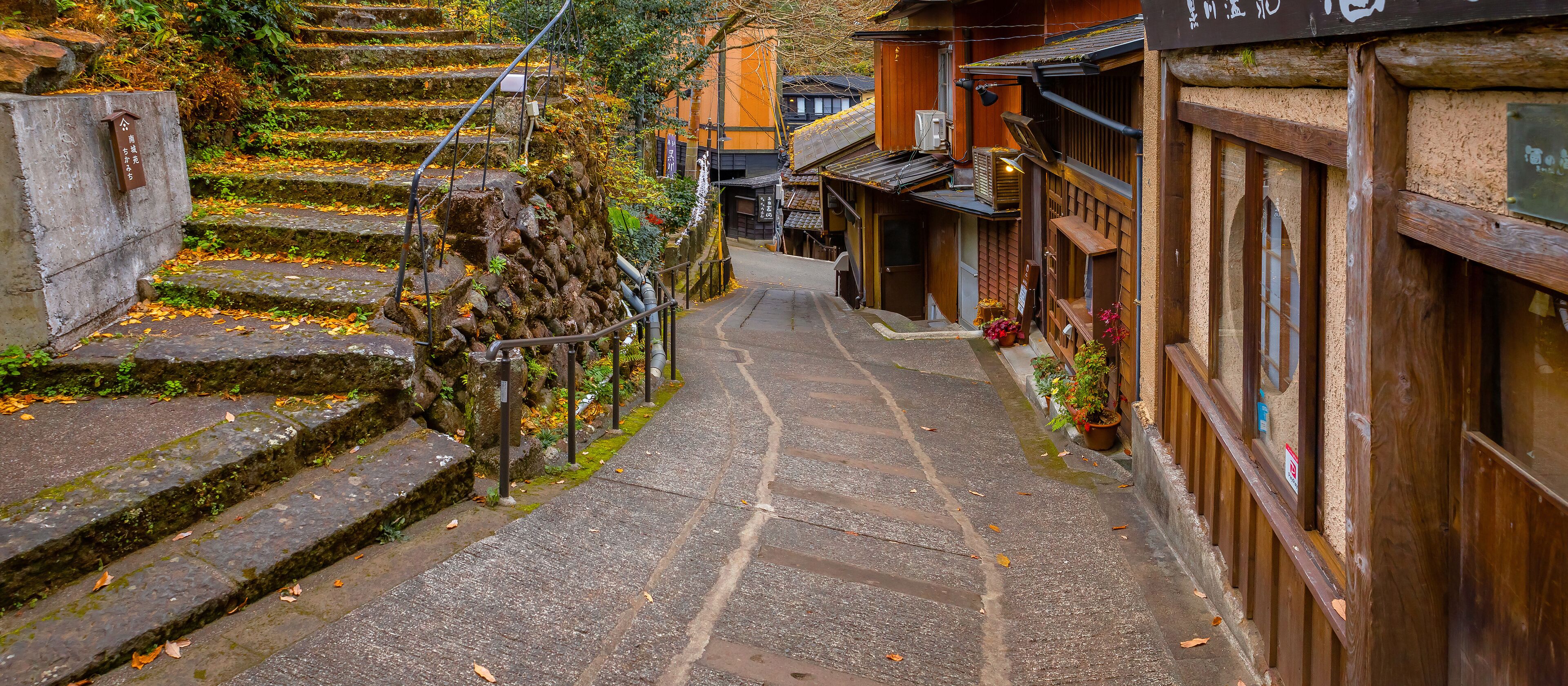 A narrow stone staircase leading up to a traditional wooden building with a signboard.