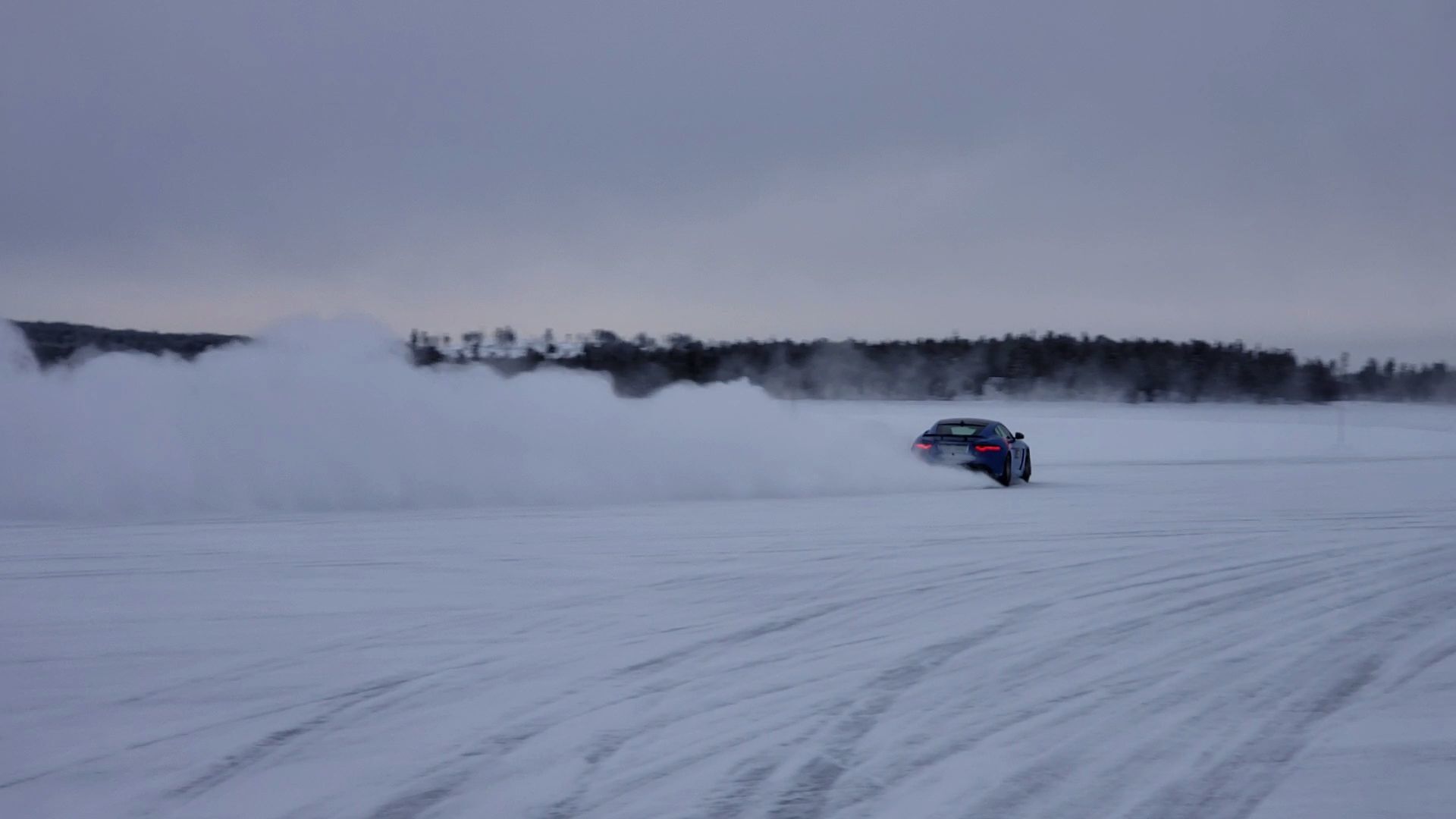 A car driving on a snowy road with tire tracks.