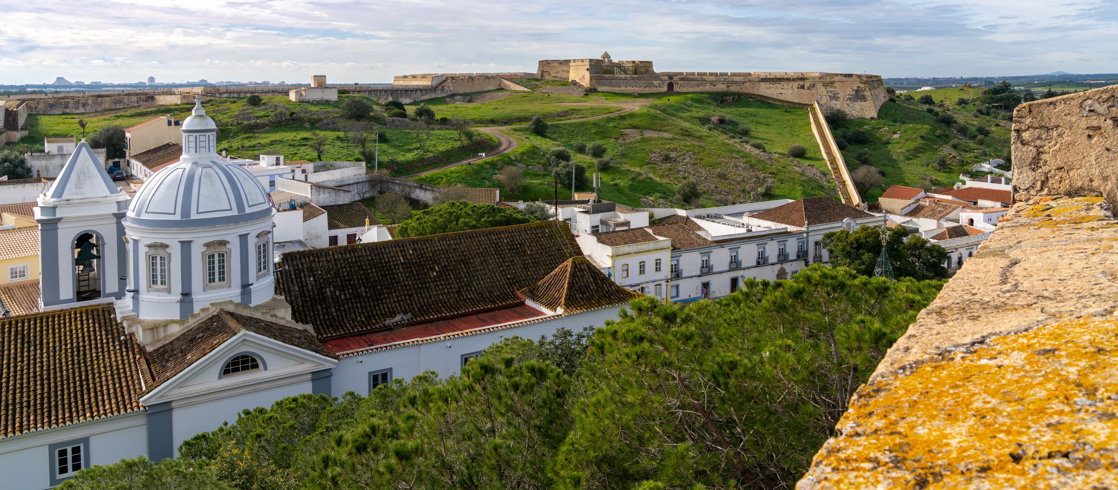 Une forteresse historique, un clocher et une église surmontée d’un dôme.