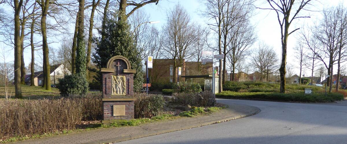 A road curving to the right with a stone monument and a bus stop sign in the foreground.