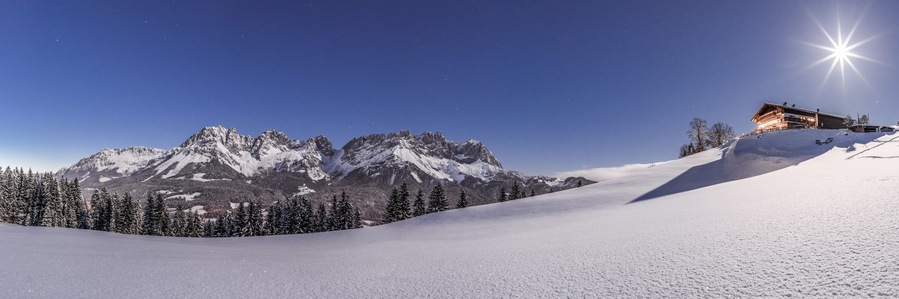 Un paisaje montañoso cubierto de nieve con un refugio en una colina.