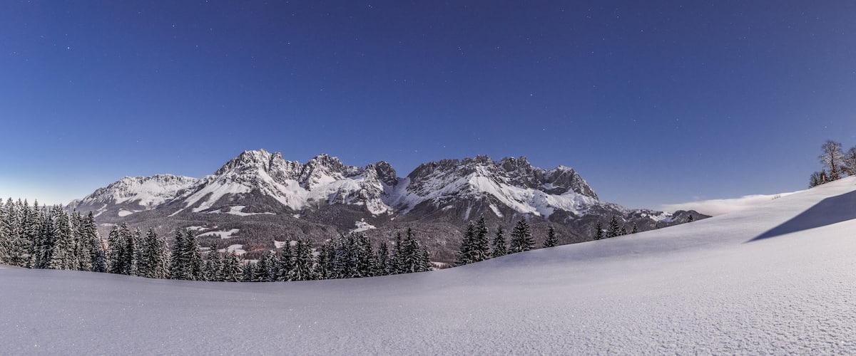 A snow-covered mountain landscape with a lodge on a hill.