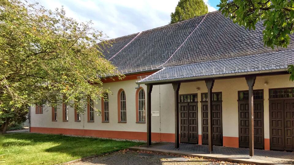 A building with a tiled roof, arched windows, and a covered entrance.