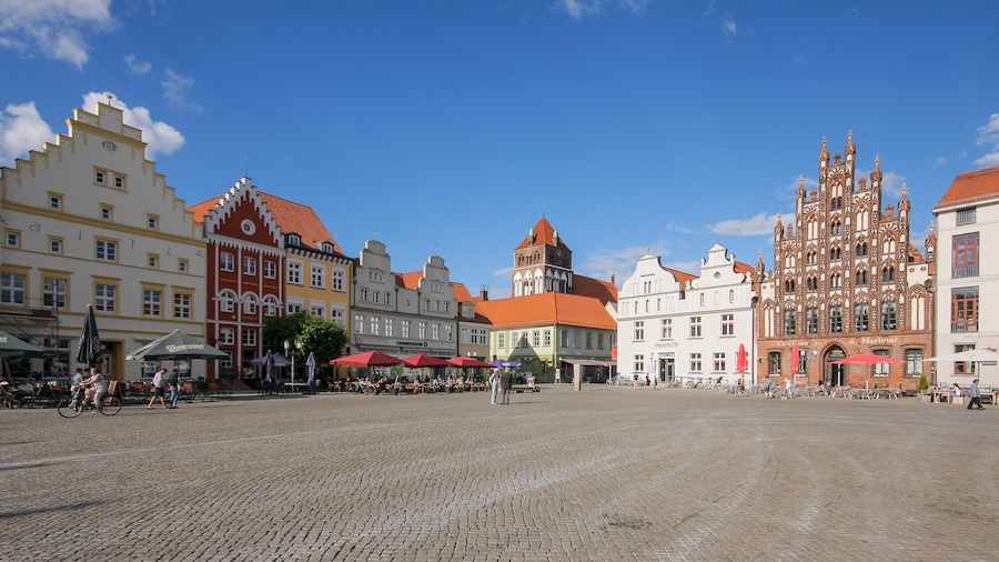 A cobblestone square with historic buildings, including a church with intricate architecture.
