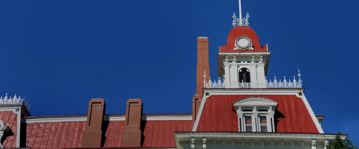 A red-roofed building with a white clock tower and a cross on top.