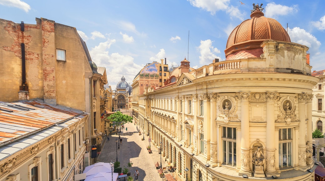 A historic street with ornate architecture, a prominent dome, and a statue.