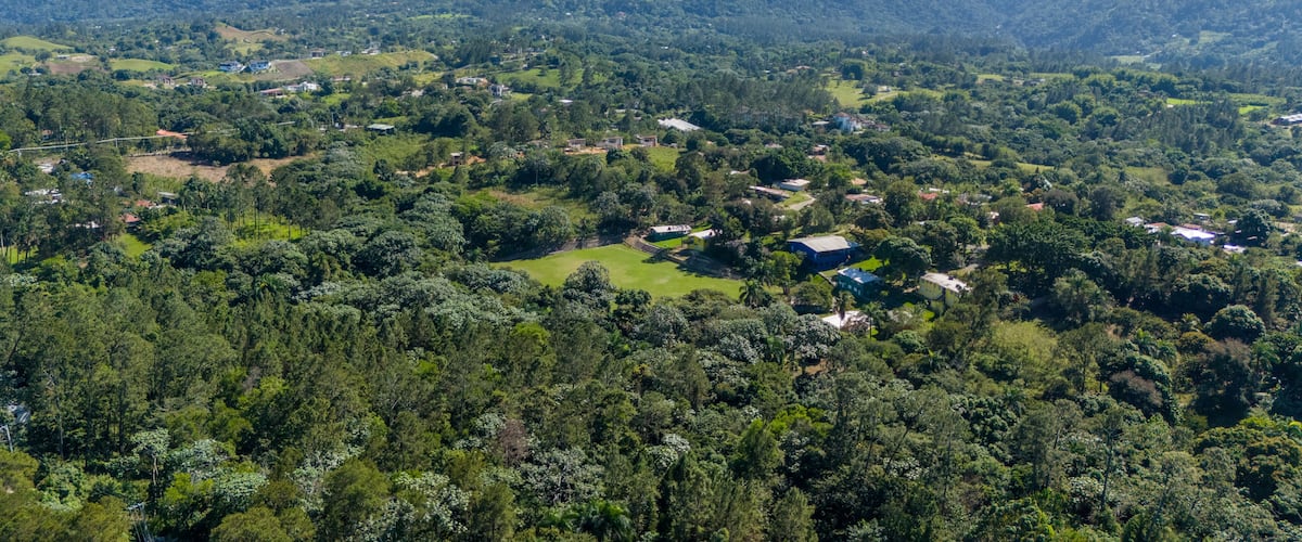A lush green valley with scattered houses and a mountain range in the background.